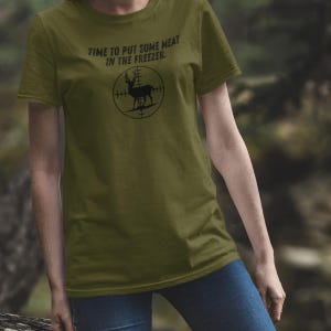 May include: A green t-shirt with the text "Time to put some meat in the freezer." and a black silhouette of a deer in a crosshair target.