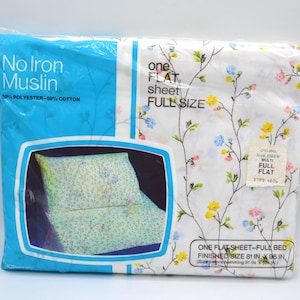 May include: A full-size flat sheet in a plastic package. The sheet is white with a floral pattern of yellow, blue, and pink flowers. The package reads "No Iron Muslin" and "50% Polyester - 50% Cotton". Finished size is 81 in x 96 in.