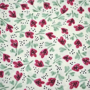 May include: A white fabric with a repeating pattern of pink flowers with green leaves and black dots.