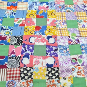 May include: A patchwork quilt featuring a grid of small fabric squares in various colors and patterns, including floral, plaid, and geometric prints. The design is punctuated by solid light green squares arranged in a repeating pattern throughout.