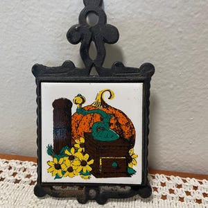 Vintage ceramic tile in a cast iron trivet.  1970’s era.  *small area of rust please see photos* priced accordingly.