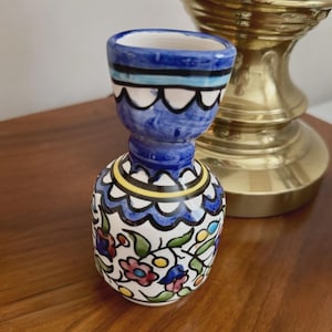 Könnte beinhalten: Kleine, handbemalte Keramikvase mit blau-weißem Oberteil und bauchigem Boden. Die Vase zeigt Blumen- und Blattmotive in Rot, Blau und Grün. Die Vase ist etwa 10 cm hoch.