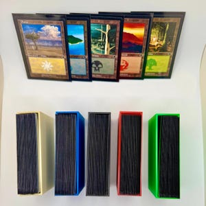 May include: Five Magic: The Gathering land cards, Plains, Island, Swamp, Mountain, Forest, are displayed above five card boxes in different colors: cream, black, blue, red, and green.