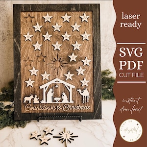 May include: Wooden advent calendar with a dark frame and a light brown interior. The calendar features star-shaped cutouts numbered 1-24, a nativity scene, and the text "Countdown to Christmas". Additional wooden stars are included.