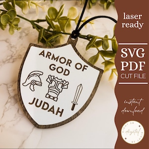 Può includere: Ornamento a forma di scudo in legno con le parole "ARMOR OF GOD" e "JUDAH" incise su sfondo bianco. Il design include illustrazioni di un elmo, un'armatura e una spada. Pronto per il laser, con file di taglio SVG e PDF.