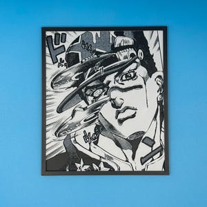 May include: Black and white framed artwork featuring a manga-style illustration of a person with a hat and stern expression. The artwork has dynamic lines and Japanese text elements, creating a sense of movement and action.