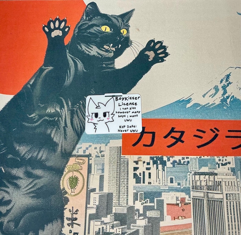 The Boykisser License charm resting on a Japanese-style desk mat featuring a large black cat and a city/mountain scene. The license shows the cute cat character and meme text.