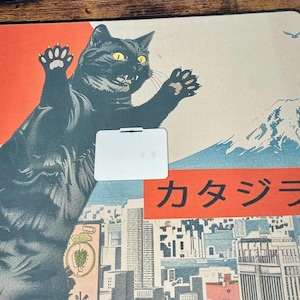 The back side of the white Boykisser License charm, resting on the Japanese-style desk mat with the black cat design.