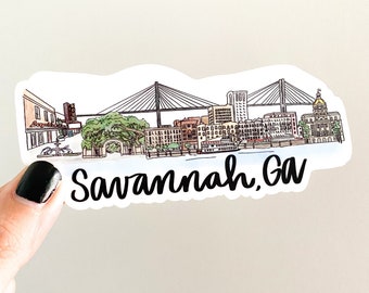May include: A sticker featuring a watercolor illustration of the Savannah, GA skyline, including a bridge, buildings, and the text "Savannah, GA" in a script font. The sticker is held by a hand.