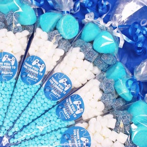May include: Blue and white party favour cones filled with sweets. The cones have a sticker with a video game controller and the text "Thank you for coming to Peter's party!"