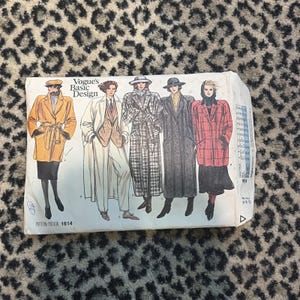 May include: A vintage Vogue's Basic Design sewing pattern, pattern number 1614, featuring illustrations of long coats and jackets. The cover shows drawings of various coat styles in different colors and patterns.
