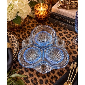 May include: A light blue glass serving dish featuring three distinct shell-shaped compartments arranged in a triangular formation. The dish has a scalloped edge and a textured, ribbed surface design, crafted from translucent pressed glass.