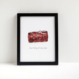 Può includere: Una stampa artistica incorniciata con un'illustrazione ad acquerello di un taglio di carne rossa. Il testo "stop staring at my rump" è sotto l'immagine. La cornice è nera.