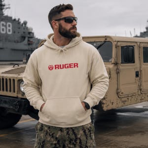 Gear up in this tan Ruger logo hoodie, built for comfort and rugged style. Perfect for range days, outdoor missions, or casual wear. Pairs seamlessly with camo pants, tactical boots, or jeans. A durable fleece essential for gun owners, military supporters, and outdoor enthusiasts who live the 2A lifestyle with pride.