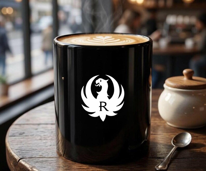 Black ceramic mug featuring a white phoenix logo with letter R. Ideal gun enthusiast mug, Ruger coffee mug, firearms brand drinkware, patriotic mug, military supporter mug, veteran coffee cup, tactical mug, range day mug, unisex coffee mug, office mug, collector mug, American pride mug, shooting sports mug, gun owner gift, second amendment mug, everyday use mug, black matte mug, logo coffee cup.