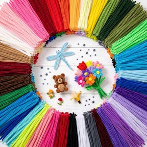 May include: A collection of multi-colored pipe cleaners arranged in a circle, surrounding a small brown teddy bear, a light blue dragonfly, a bouquet of felt flowers, tiny mushroom figures, and several small black and white googly eyes.