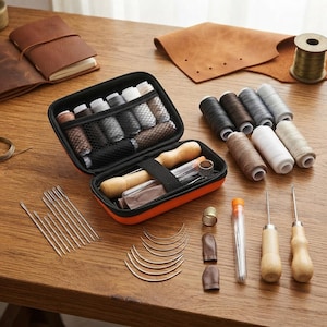 May include: A leather crafting kit featuring an orange zippered case containing multiple spools of thread, needles, and tools. Included are straight and curved needles, two wooden-handled awls, a metal thimble, and leather finger guards.