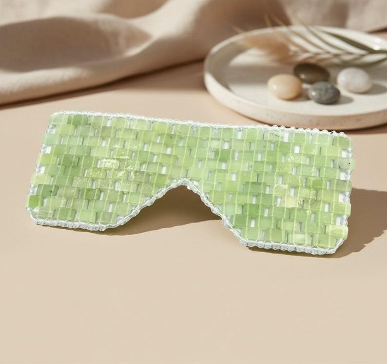 Jade Renewal Weighted Eye Mask, crafted from 100% authentic jade stone beads. Naturally cooling and calming, jade has long been cherished for its ability to reduce puffiness, soften fine lines, and restore balance. Use chilled to refresh tired eyes and soothe irritation, or warmed to relax tension and encourage circulation. More than skincare, this mask is a moment of meditation—inviting calm, clarity, and radiant renewal.