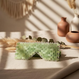 Jade Renewal Weighted Eye Mask, crafted from 100% authentic jade stone beads. Naturally cooling and calming, jade has long been cherished for its ability to reduce puffiness, soften fine lines, and restore balance. Use chilled to refresh tired eyes and soothe irritation, or warmed to relax tension and encourage circulation. More than skincare, this mask is a moment of meditation—inviting calm, clarity, and radiant renewal.