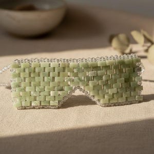 Jade Renewal Weighted Eye Mask, crafted from 100% authentic jade stone beads. Naturally cooling and calming, jade has long been cherished for its ability to reduce puffiness, soften fine lines, and restore balance. Use chilled to refresh tired eyes and soothe irritation, or warmed to relax tension and encourage circulation. More than skincare, this mask is a moment of meditation—inviting calm, clarity, and radiant renewal.