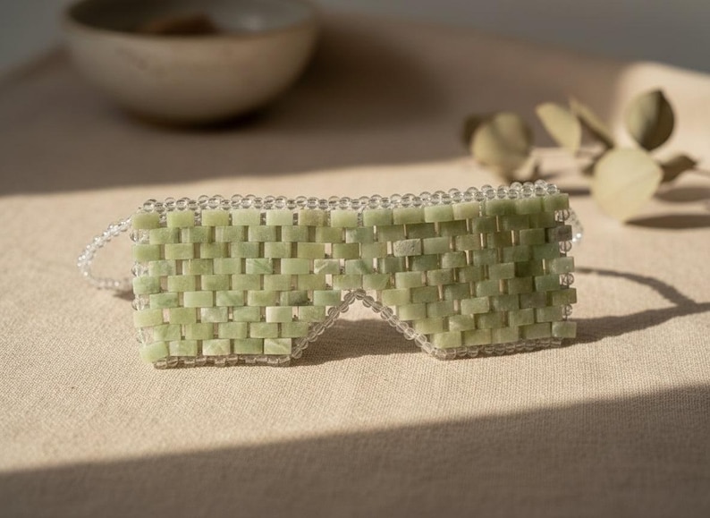 Jade Renewal Weighted Eye Mask, crafted from 100% authentic jade stone beads. Naturally cooling and calming, jade has long been cherished for its ability to reduce puffiness, soften fine lines, and restore balance. Use chilled to refresh tired eyes and soothe irritation, or warmed to relax tension and encourage circulation. More than skincare, this mask is a moment of meditation—inviting calm, clarity, and radiant renewal.