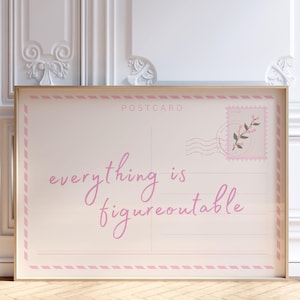 Op de afbeelding: Een ingelijste ansichtkaart met de woorden "everything is figureoutable" in roze script. De ansichtkaart heeft een roze rand en een postzegelontwerp met een bloemen takje. De lijst is licht van kleur.