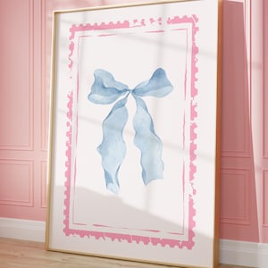 Puede incluir: Impresión artística enmarcada con una ilustración en acuarela de un lazo azul claro sobre un fondo blanco, enmarcada por un borde rosa. La obra de arte se exhibe en una habitación con paredes rosas y suelo de madera.