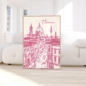 Puede incluir: Una impresi&oacute;n enmarcada con una ilustraci&oacute;n rosa y blanca de Florencia, Italia. La obra de arte representa el horizonte de la ciudad, incluyendo el Duomo y otros edificios, con la palabra "Florencia" en escritura cursiva en la parte superior.