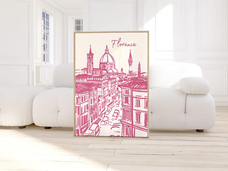 Puede incluir: Una impresi&oacute;n enmarcada con una ilustraci&oacute;n rosa y blanca de Florencia, Italia. La obra de arte representa el horizonte de la ciudad, incluyendo el Duomo y otros edificios, con la palabra "Florencia" en escritura cursiva en la parte superior.