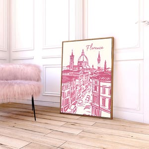 Puede incluir: Una impresi&oacute;n enmarcada de Florencia, Italia, en un estilo de boceto rosa y blanco. La obra de arte presenta la arquitectura de la ciudad, incluido el Duomo. Una silla rosa y esponjosa con patas negras est&aacute; cerca. La impresi&oacute;n est&aacute; apoyada contra una pared blanca.