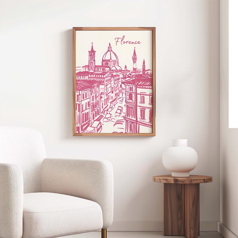 Puede incluir: Un grabado enmarcado con una ilustraci&oacute;n rosa y blanca de Florencia, Italia. La obra de arte representa la arquitectura de la ciudad, incluido el Duomo, con la palabra "Florencia" escrita encima. El marco es de madera.