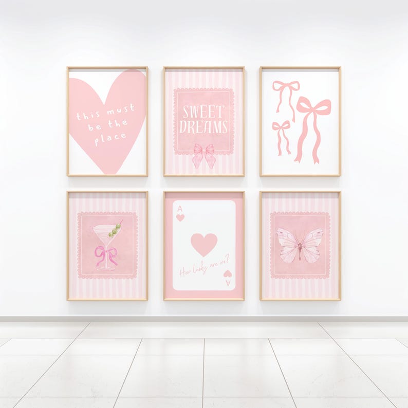 May include: Six framed pink art prints with gold frames. The prints feature a heart, bows, a martini, a playing card, and a butterfly. Text on the prints includes "this must be the place", "sweet dreams", and "How lucky are we?"