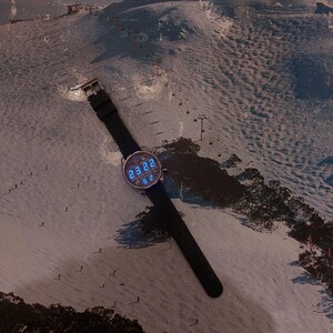 Peut inclure: Une montre-bracelet noire avec un cadran rond affichant l'heure num&eacute;rique, sur fond de paysage de montagne enneig&eacute;e. La montre a un bracelet noir et une boucle argent&eacute;e. Le fond pr&eacute;sente le texte "SKI BULLER" en rouge.
