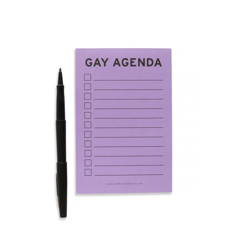 A vertical rectangle lavender notepad that reads GAY AGENDA at the top, with 11 check boxes and lines for list making. Black felt time pen on the left ready for list making.