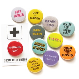 May include: A set of 12 round button badges with various phrases and designs. The badges are colorful and feature phrases like "Over Thinker", "Out of Order", "Pain Train", "Brain Fog", "Nausea", "Medical Mystery", "Fatigue Fiasco", "High Risk for COVID", "Health Care is a Human Right", "Disability Rights are Human Rights", and "Migraine Day".