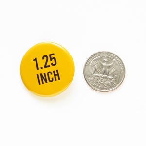 1.25" pinback button next to a quarter for size comparison