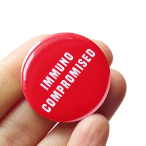 May include: Red round button with white text that reads "Immunocompromised".