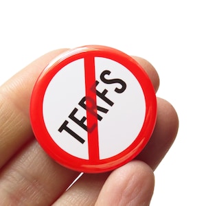 May include: A red and white button with a diagonal red line through the word "TERFS" in black letters.