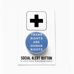 May include: A blue button with the text "TRANS RIGHTS ARE HUMAN RIGHTS" and the words "SOCIAL ALERT BUTTON" below. The text below the button reads "for common physical & psychological situations".