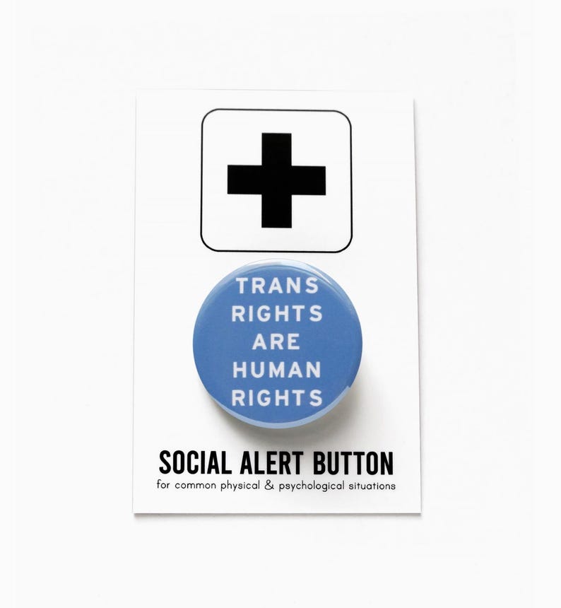 May include: A blue button with the text "TRANS RIGHTS ARE HUMAN RIGHTS" and the words "SOCIAL ALERT BUTTON" below. The text below the button reads "for common physical & psychological situations".