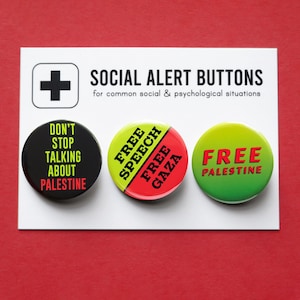 May include: Three round buttons with text on a white card against a red background. The buttons read "DON'T STOP TALKING ABOUT PALESTINE", "FREE SPEECH FREE GAZA", and "FREE PALESTINE". The card has a plus sign and the words "SOCIAL ALERT BUTTONS".