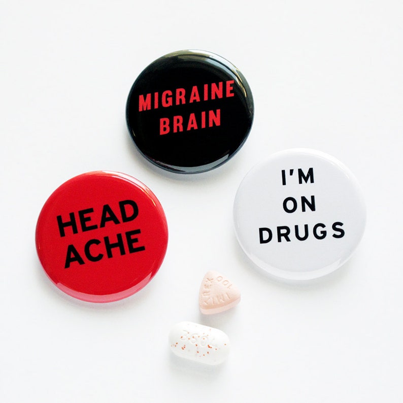 Three round pinback buttons with several pills. The buttons are red, white & black reading HEAD-ACHE, MIGRAINE BRAIN & I'M ON DRUGS.