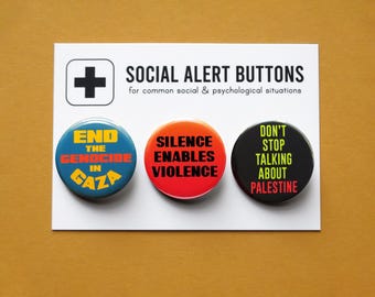 May include: A set of three round buttons with text on a white card. The buttons are blue, orange, and black, with phrases like "End the Genocide in Gaza" and "Silence Enables Violence". The card also has a plus sign and the words "Social Alert Buttons".