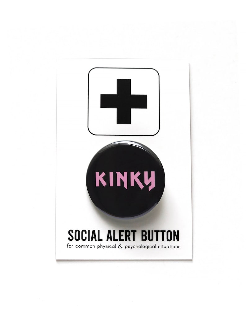 round black pinback button that reads KINKY in pink text. Button is on a Social Alert Button backing card.