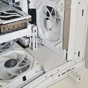 May include: A white computer case interior with multiple cooling fans and components. The case features a clean, modern design with a focus on airflow and efficient cooling. A USB drive is plugged into the front panel.
