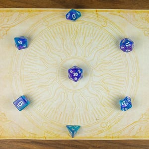 May include: A selection of blue and purple polyhedral dice arranged on a parchment-style game mat featuring a sun design. The dice, including d20, d12, d10, d8, d6, and d4 shapes, are ideal for tabletop role-playing games. The mat is decorated with a sun pattern.