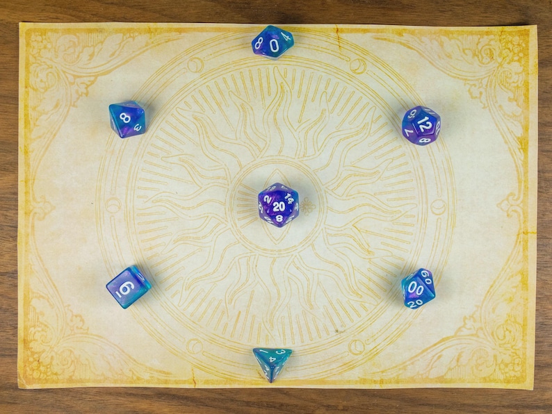 May include: A selection of blue and purple polyhedral dice arranged on a parchment-style game mat featuring a sun design. The dice, including d20, d12, d10, d8, d6, and d4 shapes, are ideal for tabletop role-playing games. The mat is decorated with a sun pattern.
