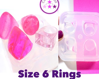 May include: A clear silicone mold with four ring cavities, next to four finished pink resin rings in various shapes. The text "Size 6 Rings" is displayed in purple. The logo "CloneMold" is in the upper left corner.