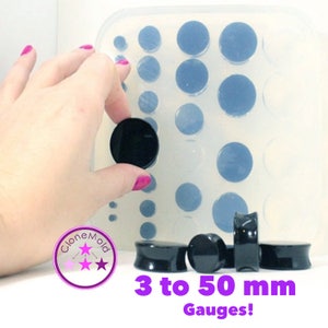 May include: A silicone mould for making ear gauges in sizes from 3 to 50 millimetres. The mould is clear and has a grid of circular impressions. Black ear gauges are shown next to the mould.