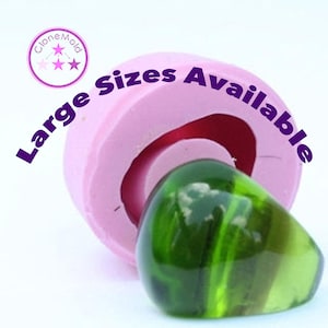 May include: A pink silicone mould with the text "Large Sizes Available" and a green glass cabochon. The mould is designed to create a cabochon shape.